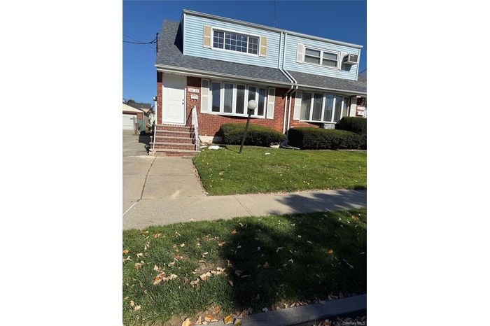 Traditional-style home featuring a front lawn, brick siding, roof with shingles, and entry steps