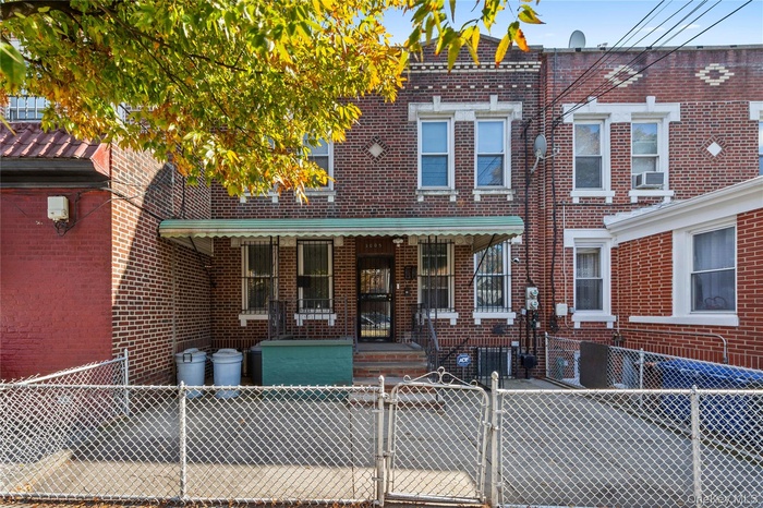 Traditional home featuring a gate, brick siding, a porch, and a fenced front yard