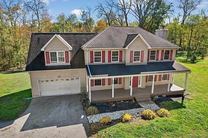View of front of home with a front yard, covered porch, asphalt driveway, and a chimney