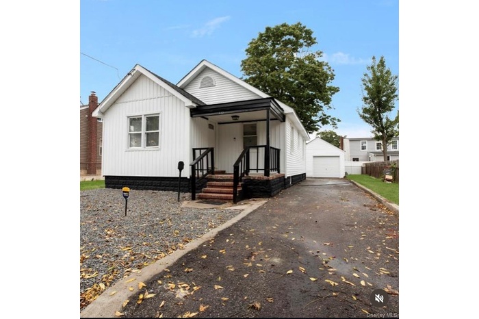 View of front of home featuring asphalt driveway, an outbuilding, and a detached garage