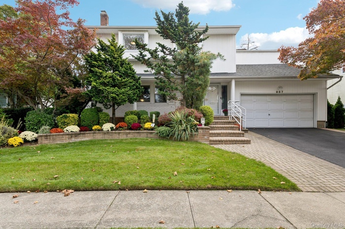 View of front of property featuring a front lawn, asphalt driveway, a garage, a chimney, and a porch