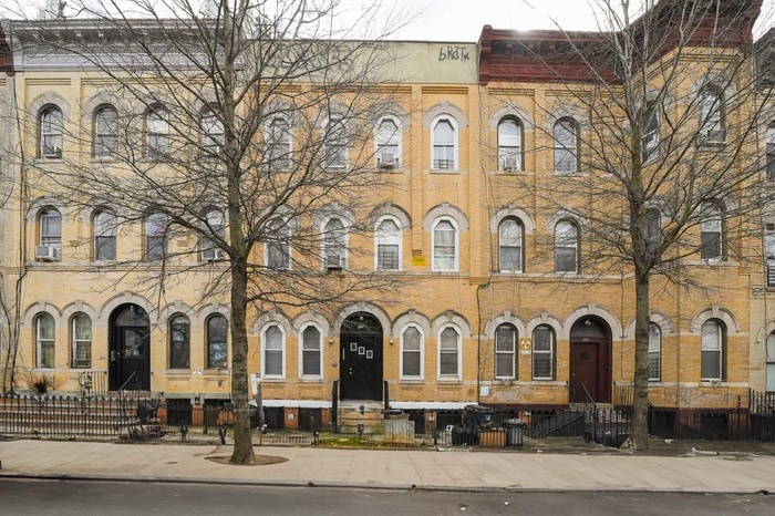 View of building exterior featuring entry steps, cooling unit, and a fenced front yard