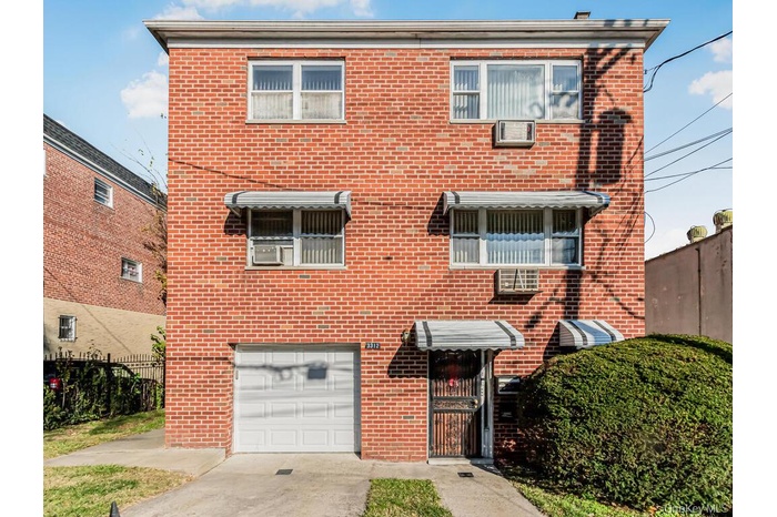 Traditional home featuring brick siding, a garage, and driveway