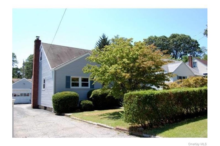 View of home's exterior featuring a detached garage, a lawn, an outbuilding, and a chimney