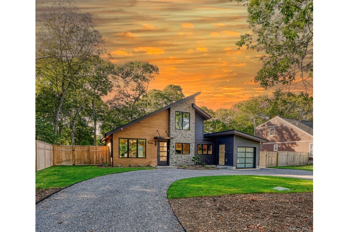 View of front of home with stone siding and curved driveway