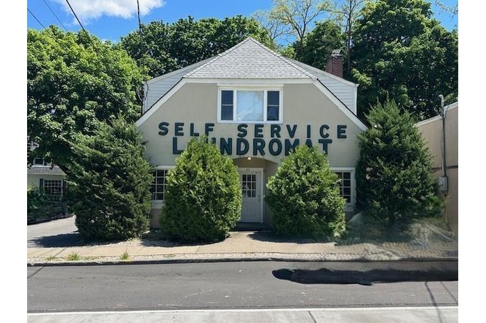 View of front facade with stucco siding, a chimney, and roof with shingles