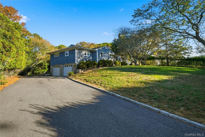 View of front of house with asphalt driveway, a garage, and a front yard