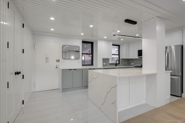 Kitchen featuring stainless steel appliances, tasteful backsplash, light stone counters, white cabinets, and recessed lighting