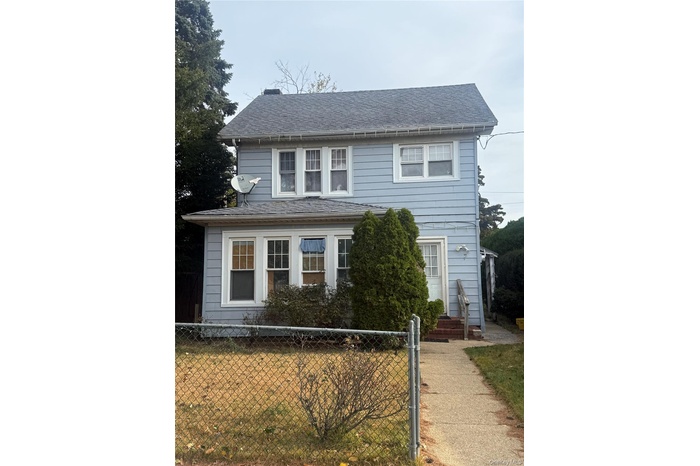 View of front facade featuring a fenced front yard and a shingled roof