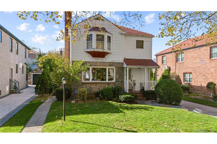 View of front facade with a front yard, stone siding, and a chimney