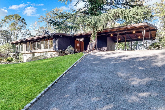 Mid-century home featuring a front lawn and driveway