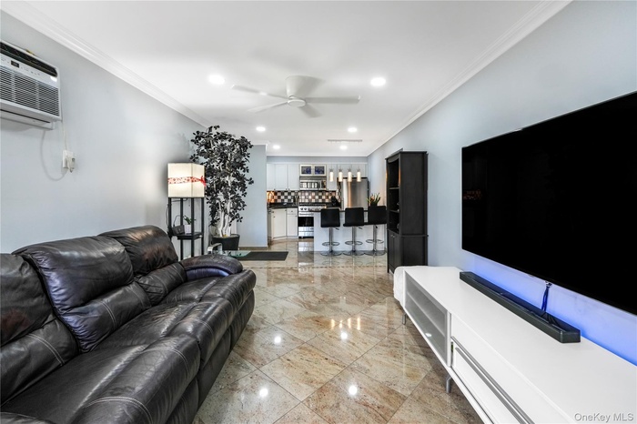 Living area with ornamental molding, recessed lighting, a ceiling fan, a dry bar, and light marble finish flooring