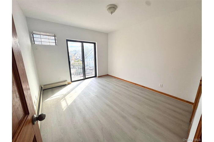 Unfurnished room featuring wood finished floors and a baseboard heating unit