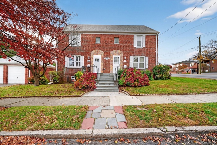 Colonial inspired home featuring brick siding, a front lawn, and a garage