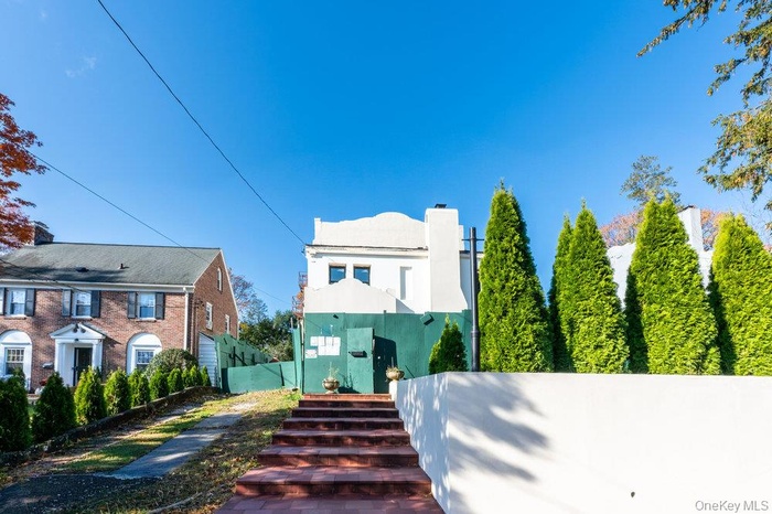 View of front of house with a chimney, stairway, and stucco siding