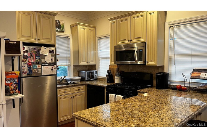 Kitchen featuring a peninsula, ornamental molding, black appliances, healthy amount of natural light, and backsplash