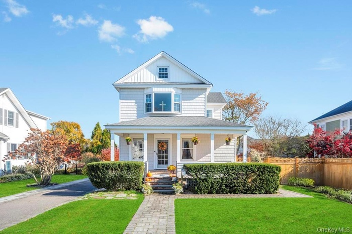 View of front of property with a front lawn, a porch, and roof with shingles