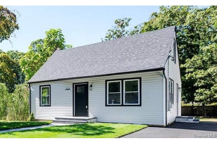 Cape cod-style house featuring a front yard and roof with shingles