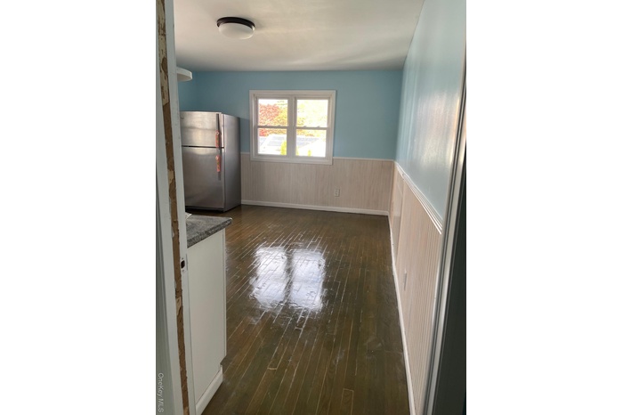 Unfurnished dining area with wainscoting, dark wood finished floors, and wood walls