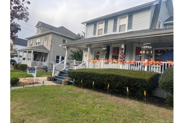 View of front facade with a large porch and a front yard