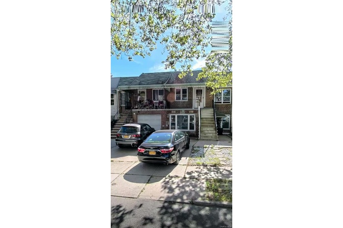 View of front of house featuring stairway, brick siding, a garage, and driveway
