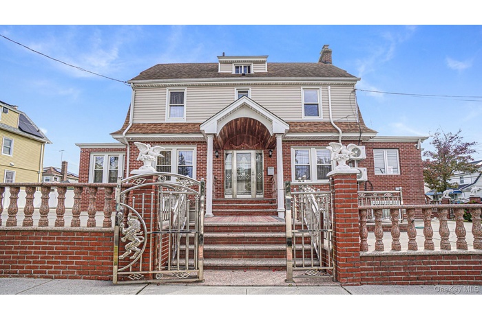 View of front of house featuring a gate, a chimney, brick siding, roof with shingles, and a fenced front yard