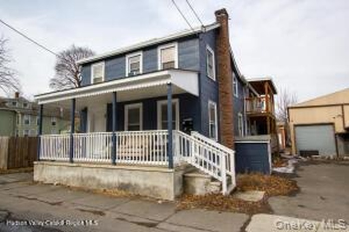 View of front facade featuring a porch and a chimney