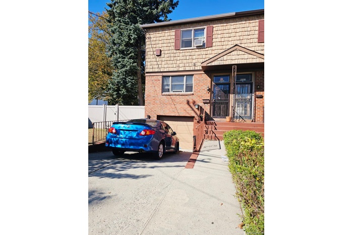 Colonial inspired home with asphalt driveway, brick siding, an attached garage, and a gate
