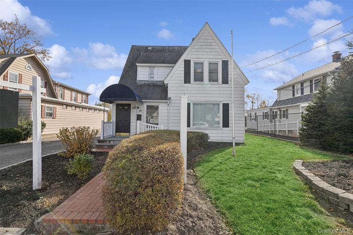 View of front of house featuring a front yard and roof with shingles