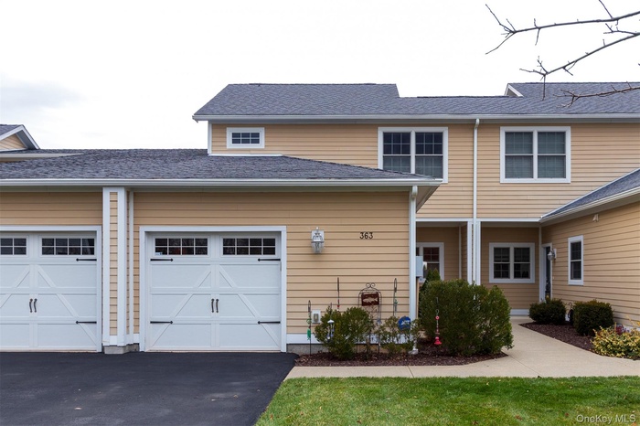 Traditional-style home featuring a shingled roof and driveway