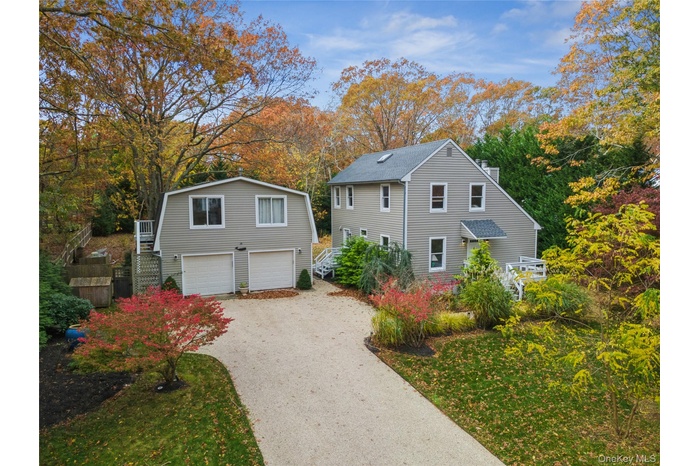 View of front of property featuring stairway, driveway, an attached garage, and view of scattered trees