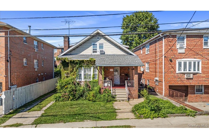 Bungalow-style house featuring roof with shingles, covered porch, a chimney, brick siding, and a front yard