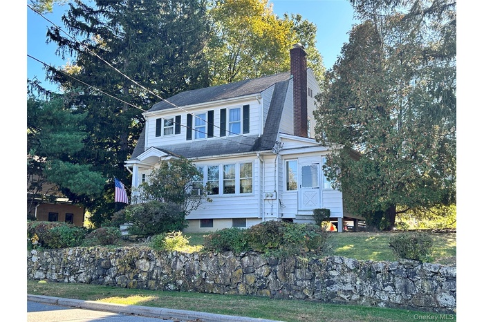 View of front of home featuring a chimney, a gambrel roof, a shingled roof, and a front yard