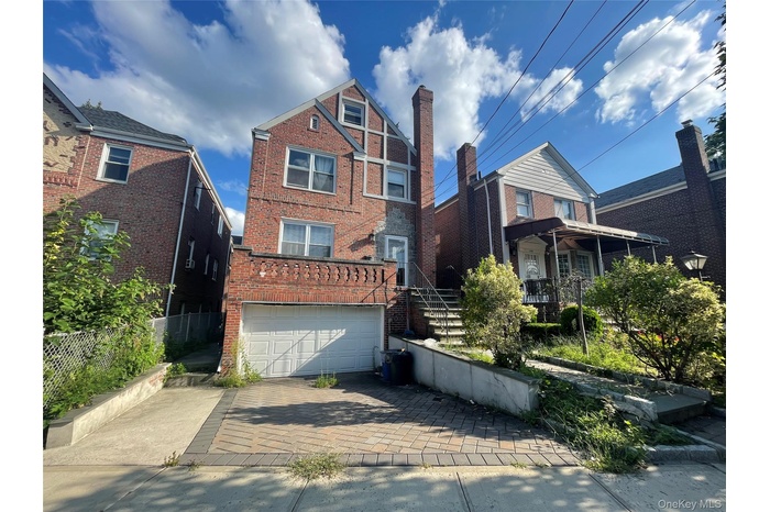 View of front of property with brick siding, decorative driveway, and an attached garage