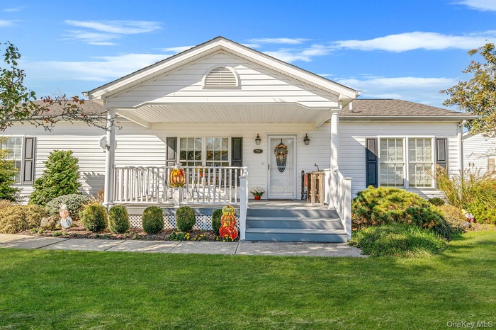 View of front of property with covered porch, a front lawn, and roof with shingles