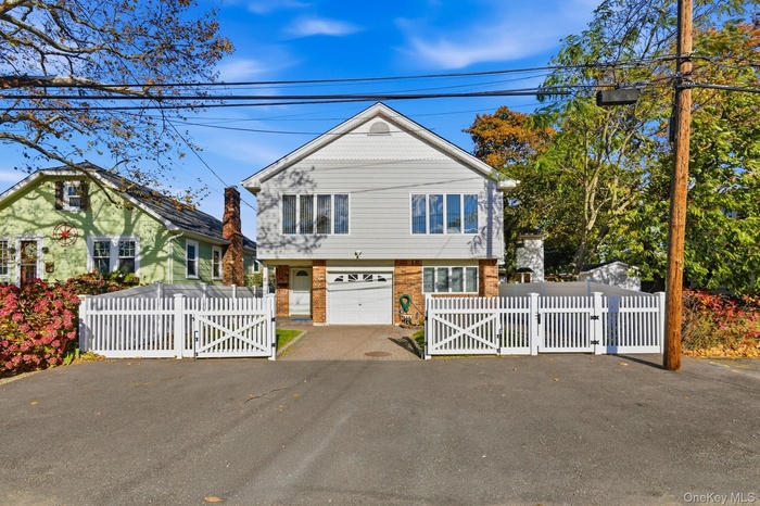 View of front of home with a gate, driveway, brick siding, and an attached garage