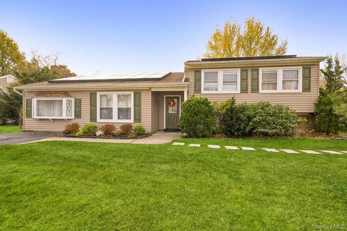 Split level home with roof mounted solar panels and a front lawn