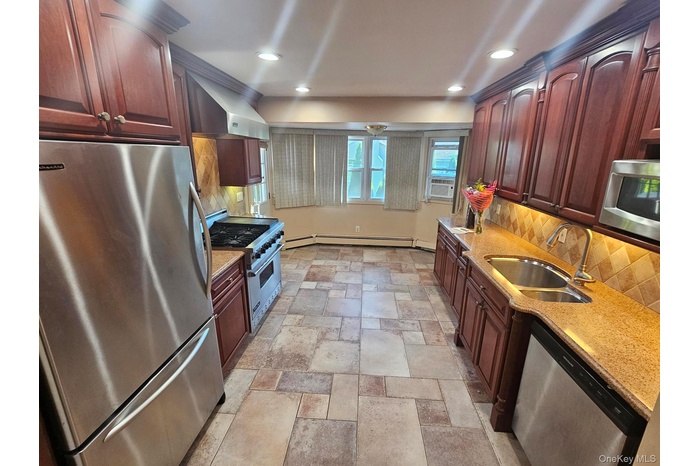Kitchen featuring appliances with stainless steel finishes, wall chimney exhaust hood, decorative backsplash, light stone counters, and recessed light