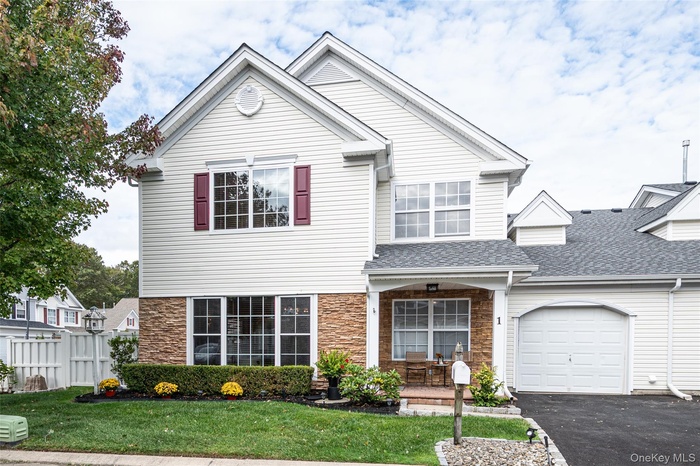 Traditional-style home with asphalt driveway, stone siding, roof with shingles, and a garage