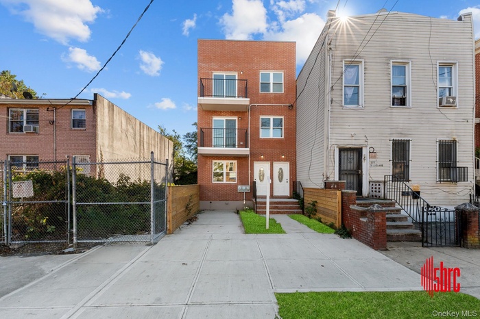 View of front of home with a gate, brick siding, and a balcony