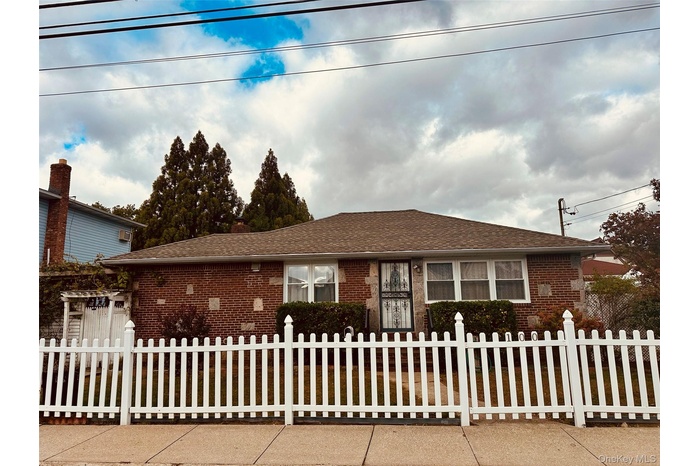 View of front of home with brick siding, a fenced front yard, and a shingled roof