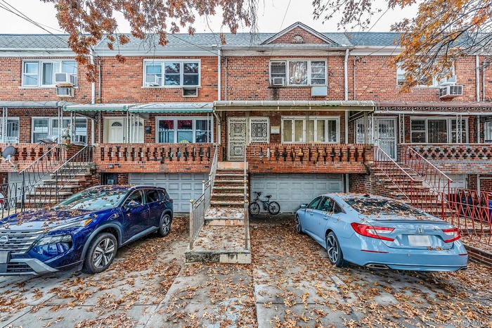 View of front of house featuring brick siding, stairs, a garage, and driveway
