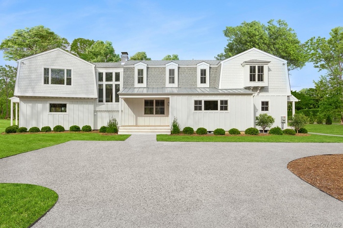 View of front of property featuring a gambrel roof, a front lawn, and board and batten siding