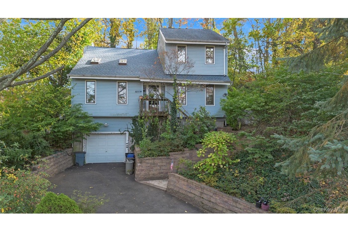 View of front of home with a shingled roof, driveway, and an attached garage