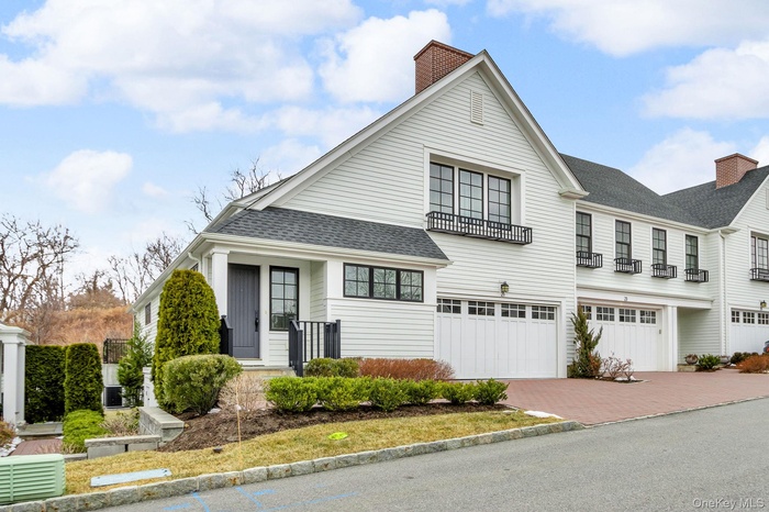 View of front of home featuring an attached garage, decorative driveway, a shingled roof, and a chimney