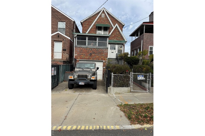 View of front of home featuring a gate, brick siding, concrete driveway, and a fenced front yard