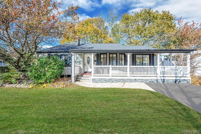 Ranch-style home featuring a porch, a front lawn, and roof with shingles