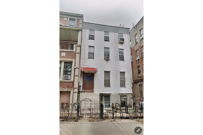 View of building exterior with a fenced front yard and cooling unit