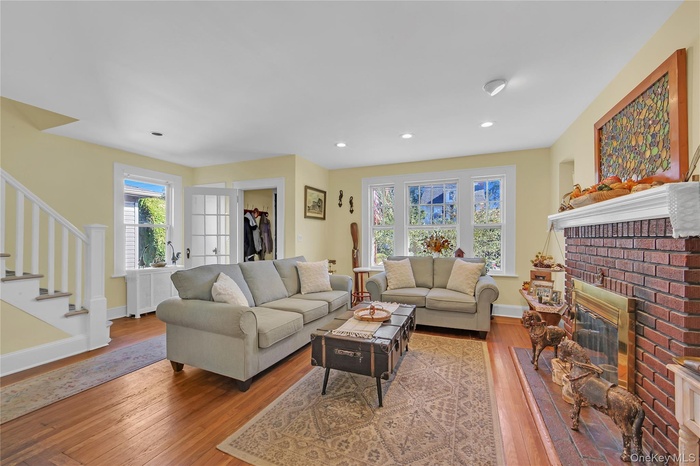 Living area featuring stairs, light wood finished floors, a fireplace, and recessed lighting