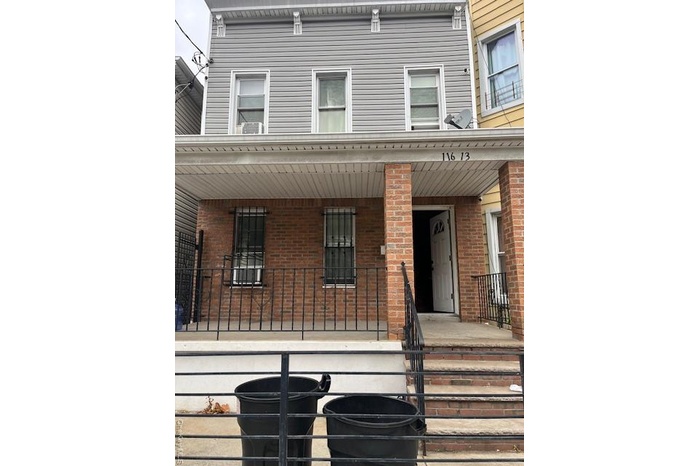 View of exterior entry with brick siding and covered porch